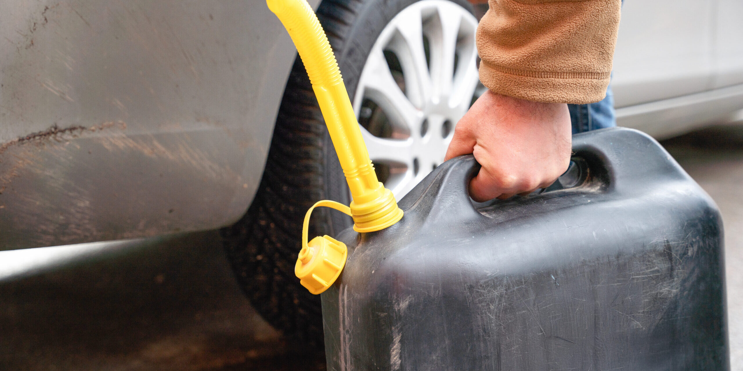 Person Filling Vehicle With Fuel From Portable Canister On Roadside